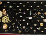 de nombreuses bagues différentes dans une vitrine posée sur une table rouge