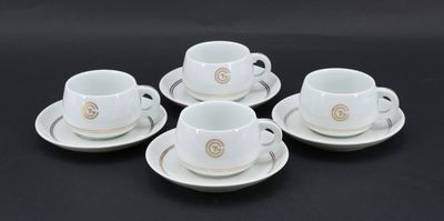 quatre tasses à café blanches avec leurs soucoupes, posées sur une table noire