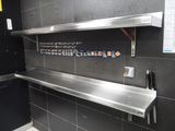 une photo d'une étagère en acier inoxydable dans des toilettes publiques