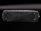 an old black leather bag with rivets and brass hardware on a black background