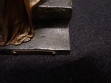 a bronze statue of a woman standing on a step