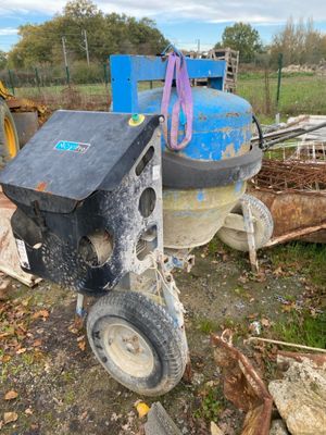 a machine that is sitting on the ground next to a pile of wood