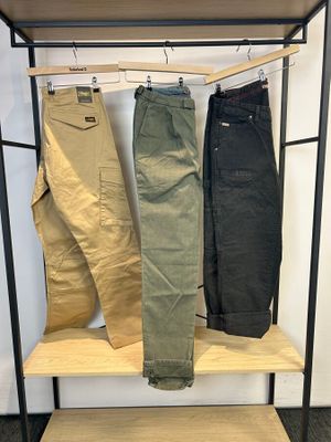 trois paires de pantalons pour homme suspendues à un portant dans une pièce