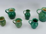 five green vases with handles on a white surface
