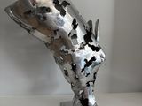 a metal sculpture of a head on a metal stand