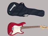 une guitare électrique rouge et un étui noir sur fond gris