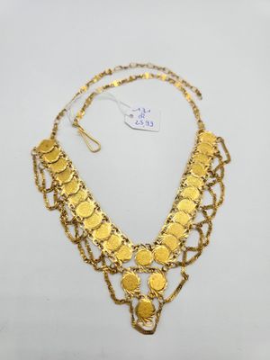 un collier en or orné de pièces et de chaînes sur fond blanc