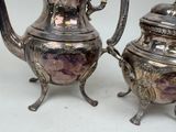 two silver teapots sitting next to each other on a table
