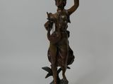 bronze statue of a woman holding a sword and a bird on a pedestal