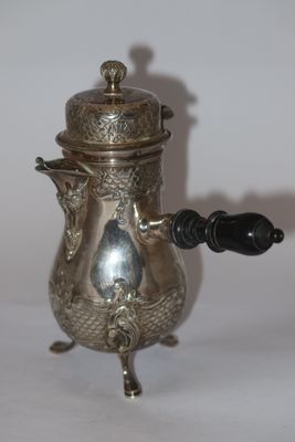 a silver tea pot with a black handle on a table