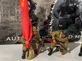 three figurines of soldiers holding a red flag and a red flag