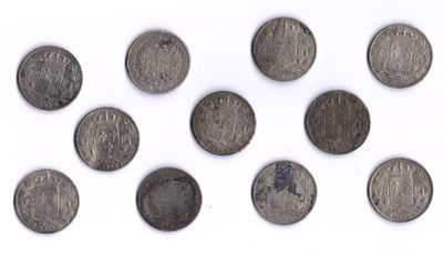 Plusieurs pièces anciennes sont disposées en cercle sur une surface blanche