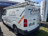 a van parked in front of a building with a ladder on the roof
