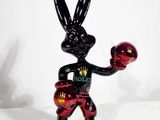 statue représentant un lapin noir muni d'un gant de boxe rouge et tenant une balle rouge