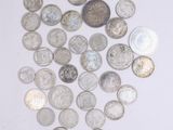 a pile of silver and silver coins on a white surface