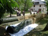 a large roll of hay on the ground next to a house