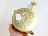 a person holding a gold object with a sticker on it