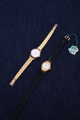 two watches that are sitting on a blue surface