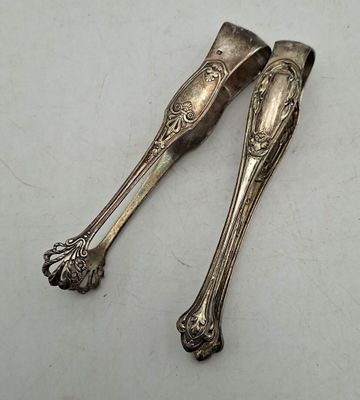 une paire de cuillères anciennes en argent posées sur une surface blanche