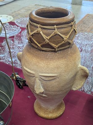 a large brown vase sitting on top of a red table cloth