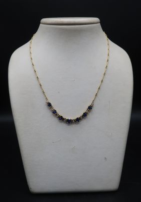 a gold necklace with blue sapphires on a mannequin