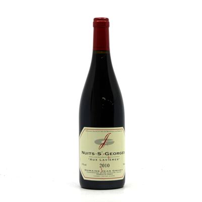 the bottle of red wine is sitting on a white surface