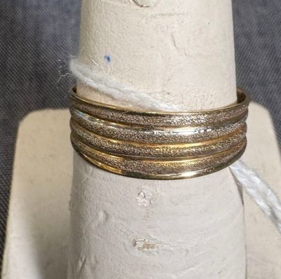 une pile de trois bagues en or posée sur un porte-bagues