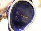 someone is holding a blue vase with a gold inscription on it