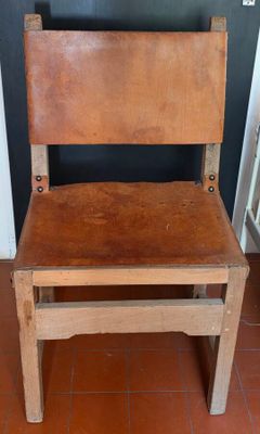 une chaise en bois avec une assise en cuir, posée sur un sol carrelé