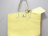 yellow straw tote bag hanging from a hook on a wall
