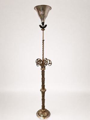 an antique brass floor lamp with a glass shade on top of it