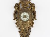 une horloge dorée accrochée au mur, sur fond blanc