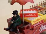 a miniature model of a coca cola cart with a man sitting in it