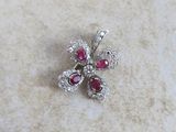 un gros plan sur une broche en forme de fleur, sertie de diamants et de rubis