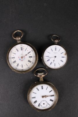 three antique pocket watches sitting on top of a black surface