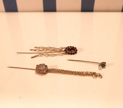 deux paires de boucles d'oreilles avec des chaînes et des perles posées sur une table blanche