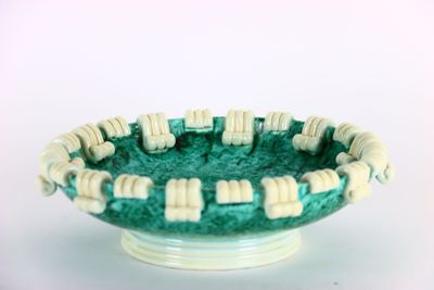 un bol vert contenant des perles blanches, posé sur une surface blanche