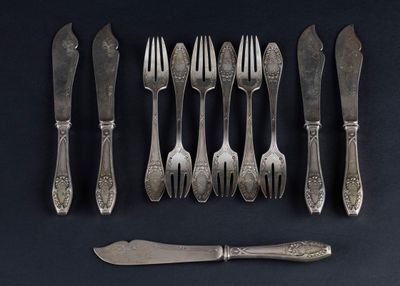 six forks and a knife on a black table