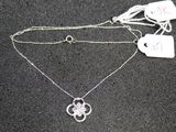 two silver necklaces on a black surface with a price tag