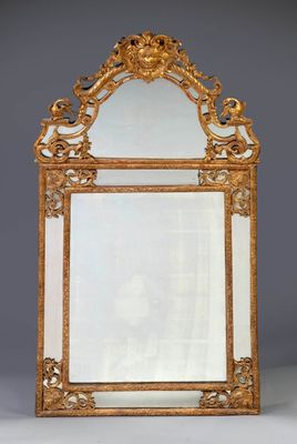 un miroir richement sculpté, avec un cadre doré sur fond gris