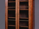 an antique walnut bookcase with glass doors