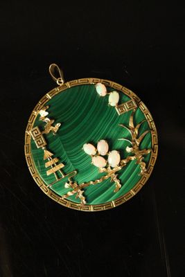 gold and green broochle with flowers on it on a black surface