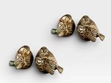 three bronze birds sitting on top of each other on a white surface