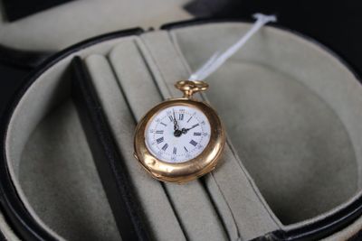 une montre de poche en or posée dans un écrin sur une table