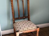 une chaise en bois avec un coussin posé dessus, dans une pièce