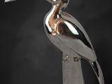 silver sculpture of a bird on a pedestal against a black background