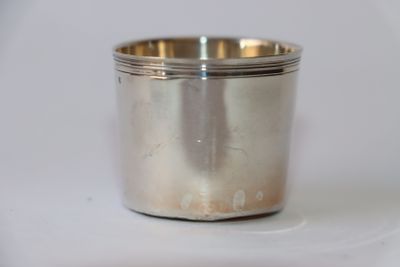 une tasse en argent posée sur une surface blanche