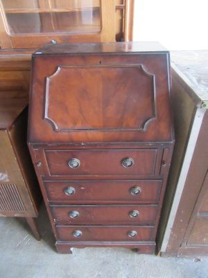 a small wooden cabinet with drawers next to a dresser