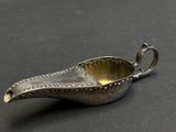 a small silver sauce boat on a black surface