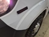 a close up of a white truck with a light on it ' s headlight